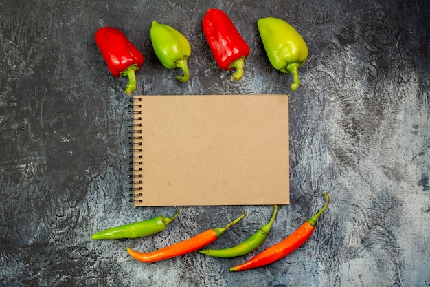 Top view fresh peppers with notepad on light-grey table