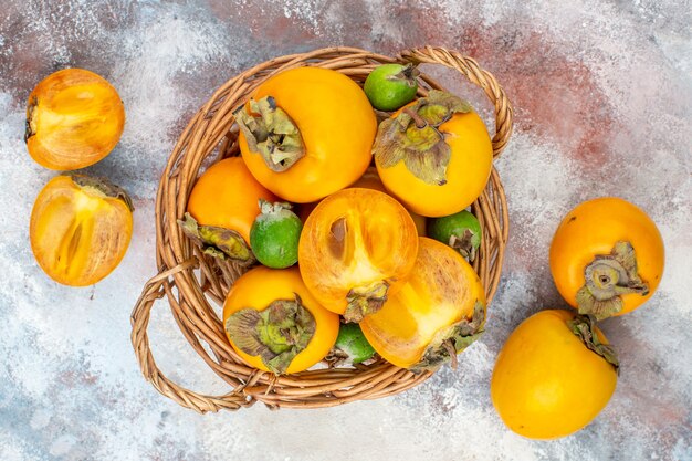 Top view fresh persimmons feykhoas in wicker basket on nude background