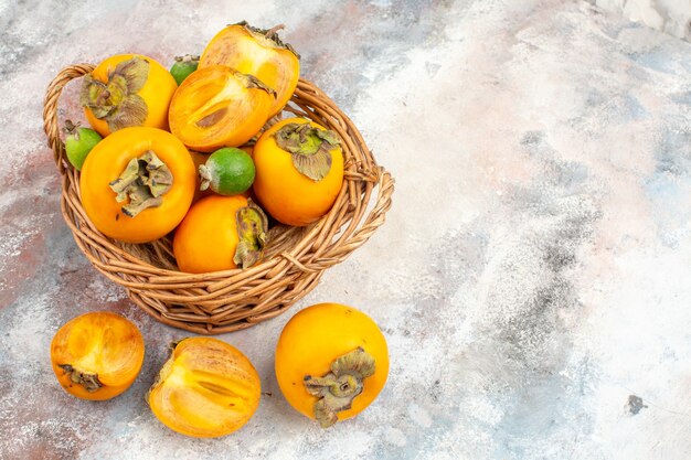 Top view fresh persimmons feykhoas in wicker basket on nude background