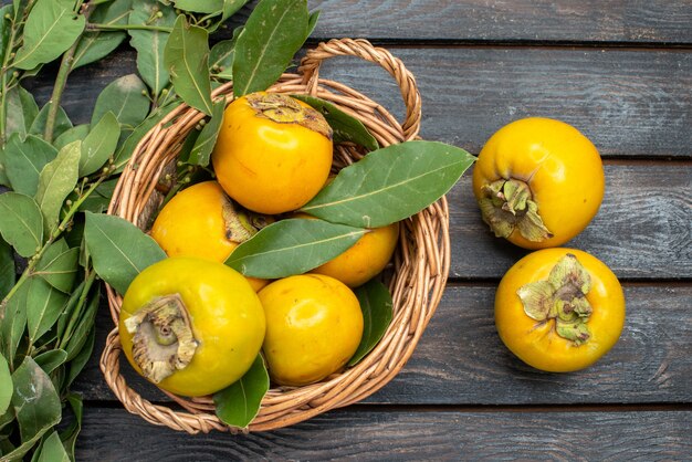 Top view fresh persimmons inside basket on the wooden table, fruit mellow ripe