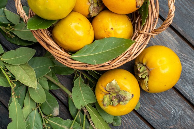 Top view fresh persimmons inside basket on wooden table, fruits mellow ripe