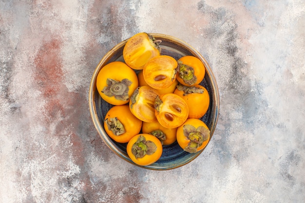 Top view fresh persimmons in round wood box on nude background