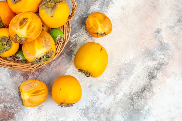 Top view fresh persimmons in wicker basket on nude background