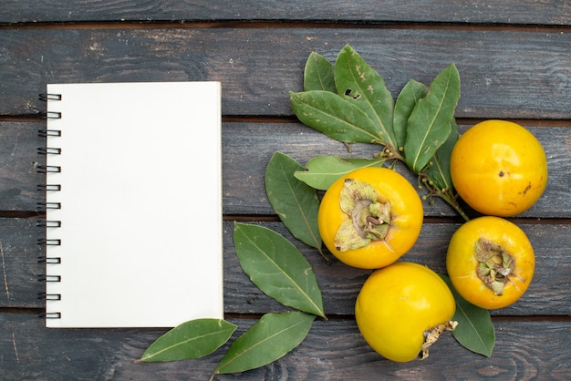 Foto gratuita vista dall'alto cachi freschi sulla tavola rustica in legno, frutta matura pastosa