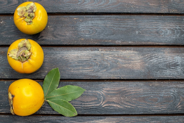 Free photo top view fresh persimmons on wooden rustic table, ripe mellow fruit