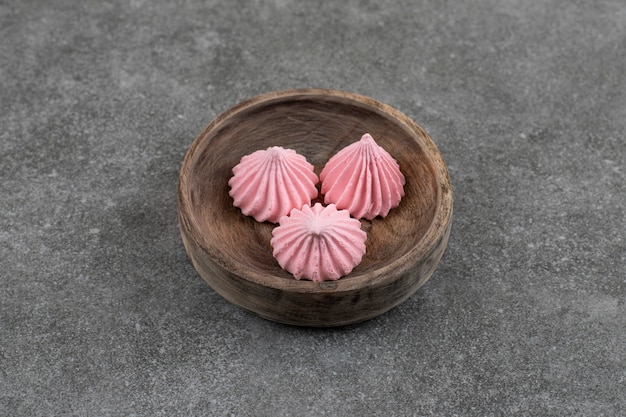 Top view of fresh pink meringue cookies in wooden bowl