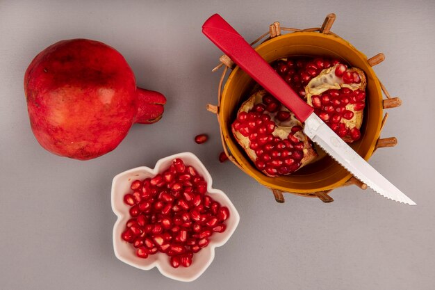 Top view of fresh pomegranate on a bucket with knife with pomegranate seeds on a bowl