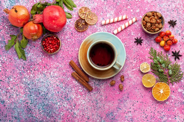 밝은 분홍색 표면에 녹색 잎과 차 한잔과 함께 상위 뷰 신선한 석류