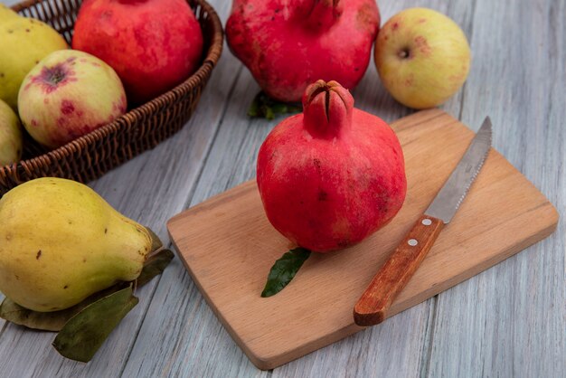 사과와 quinces 회색 배경에 고립 된 칼으로 나무 주방 보드에 신선한 석류의 상위 뷰