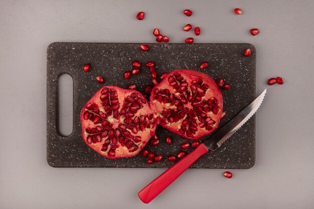 Top view of fresh pomegranates on a black kitchen board with knife