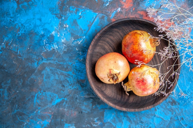 Top view fresh pomegranates in a bowl on blue background