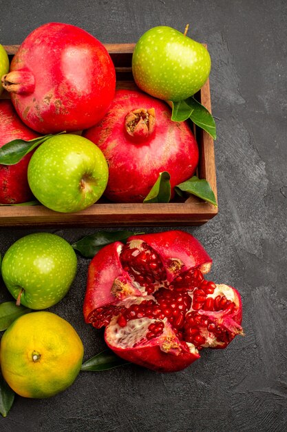 Top view fresh pomegranates with tangerines and apples on a dark surface ripe color fruit