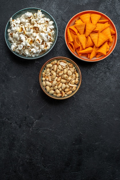 Top view fresh popcorn with nuts and chips on dark background chips snack crisp cracker