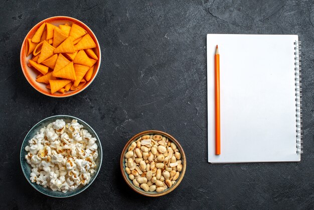 Top view fresh popcorn with nuts and chips on dark desk chips snack crisp cracker