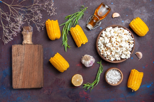 Foto gratuita vista dall'alto popcorn fresco con calli gialli crudi sulla pianta del film di mais popcorn snack superficie scura