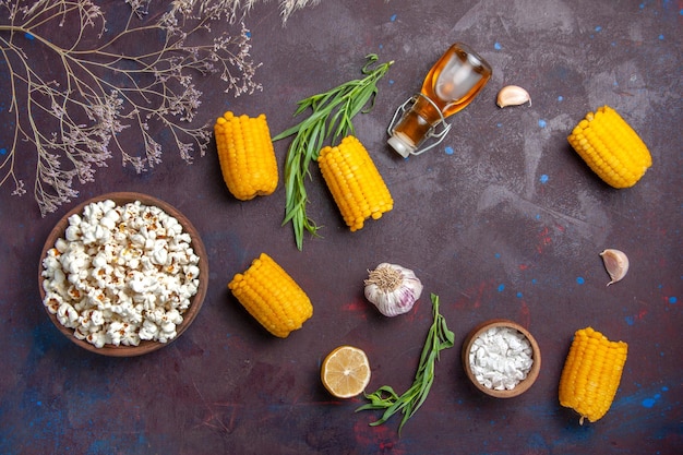 Foto gratuita vista dall'alto popcorn fresco con calli gialli crudi sulla pianta del film di mais popcorn snack superficie scura