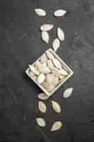 Foto gratuita vista dall'alto semi di zucca freschi sullo sfondo scuro granuli di semi di oscurità foto