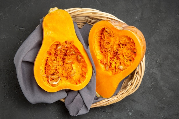 Top view of fresh pumpkin sliced inside basket on a dark background