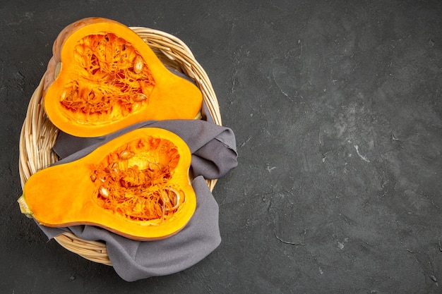 Top view of fresh pumpkin sliced inside basket on dark background