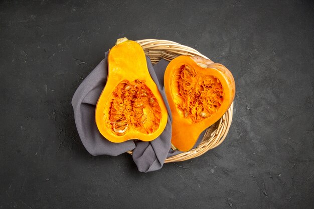 Top view of fresh pumpkin sliced inside basket on dark background