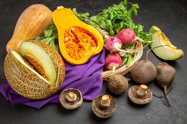 Top view of fresh pumpkin with melon and greens on dark background