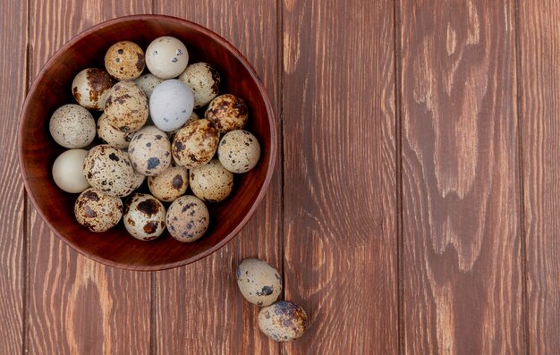 Top view of fresh quail eggs with cream colored shells on a wooden background with copy space