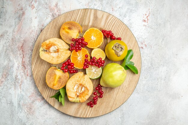 Вид сверху свежей айвы с другими фруктами на белом столе, свежих спелых фруктов