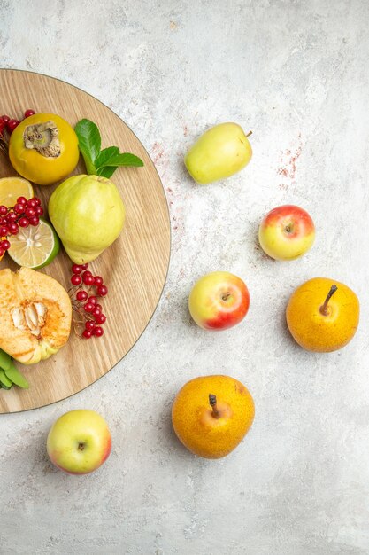 Вид сверху свежей айвы с другими фруктами на белом столе, спелые фрукты, спелые свежие
