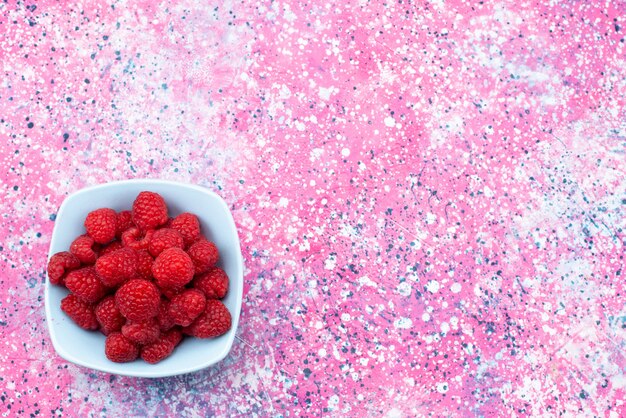 Top view fresh raspberries inside blue plate on the colored background berry fruit color vitamine