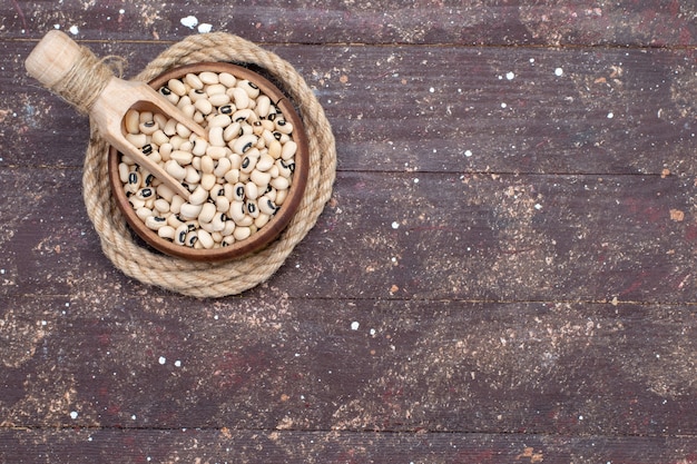 Vista dall'alto di fagioli crudi freschi all'interno della ciotola marrone su legno rustico marrone, fagioli fagioli crudi alimentari