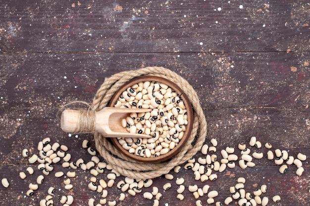 茶色のボウルの中の新鮮な生豆の上面図で、茶色の食品生豆ハリコット全体に広がっています