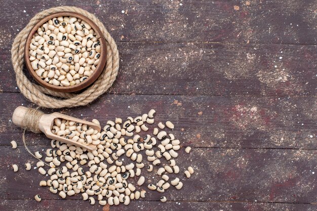 Top view of fresh raw beans inside brown bowl with rope on brown desk, food raw bean haricot