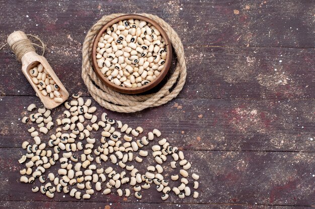 茶色のボウルの内側と外側の新鮮な生豆の上面図は、茶色の食品生豆ハリコット全体に広がっています