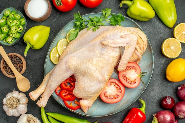 Вид сверху свежего сырого цыпленка с разными овощами на темном столе, спелый салат, еда, здоровая диета