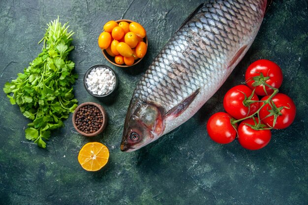 暗い背景に緑とトマトと新鮮な生の魚の上面図