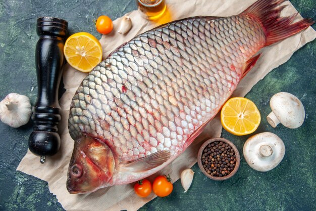 top view fresh raw fish with mushrooms and seasonings on dark-blue background