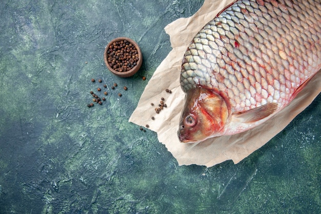 Foto gratuita vista dall'alto pesce crudo fresco con pepe su sfondo blu scuro