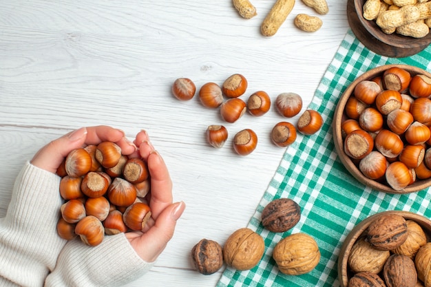 Top view fresh raw hazelnuts with peanuts and walnuts on white table