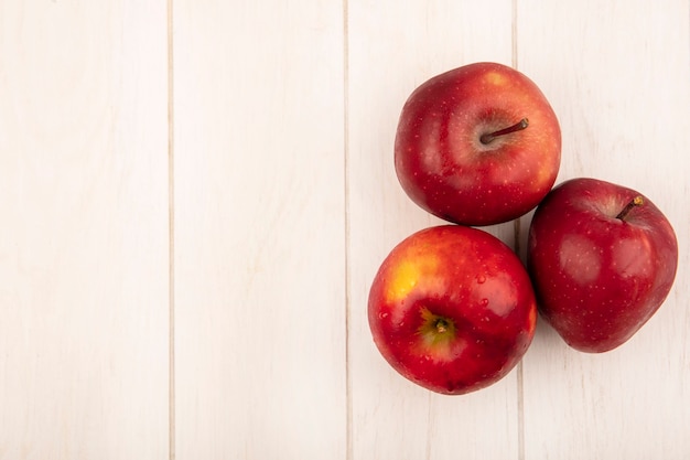 Вид сверху свежих красных яблок, изолированных на белой деревянной поверхности с копией пространства