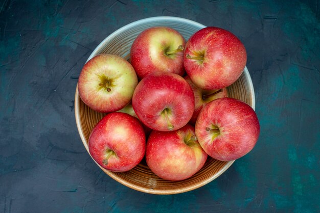 Вид сверху свежие красные яблоки сочные и мягкие внутри тарелки на темно-синем столе фрукты свежие спелые спелые витамины