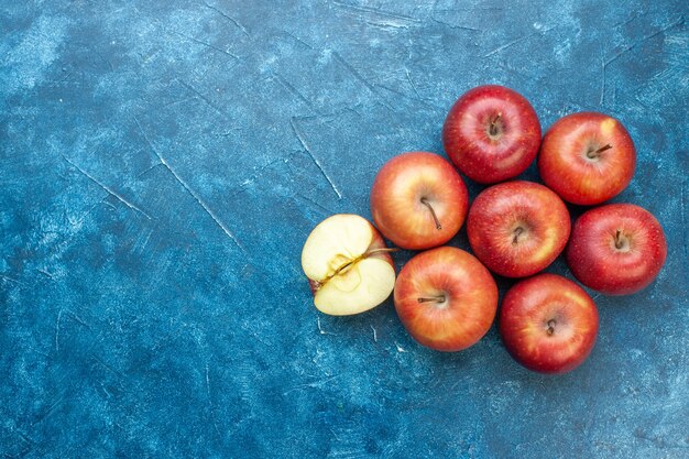 Вид сверху свежие красные яблоки, выложенные на синем столе, спелые фрукты