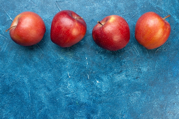 무료 사진 파란색 탁자에 늘어선 신선한 빨간 사과