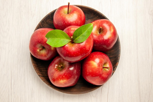Вид сверху свежие красные яблоки, спелые и спелые фрукты на белом столе, фруктовое дерево красного цвета, свежее растение