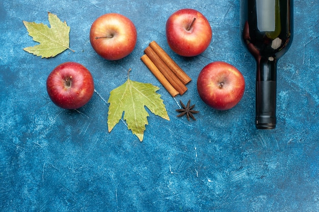 파란색 책상에 와인 한 병이 있는 신선한 빨간 사과 잘 익은 과일 알코올 색상 사진 나무