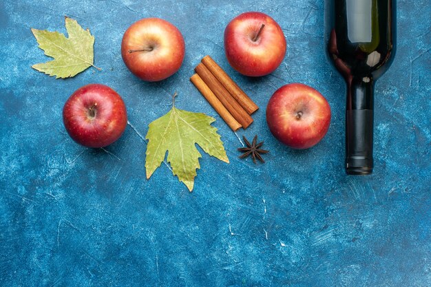 Top view fresh red apples with bottle of wine on blue desk ripe fruit alcohol color photo tree