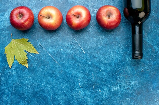 Top view fresh red apples with bottle of wine on a blue table ripe fruit alcohol color photo tree