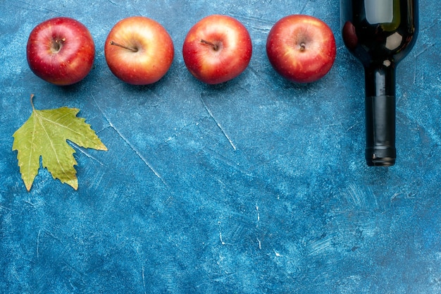 Top view fresh red apples with bottle of wine on a blue table ripe fruit alcohol color photo tree