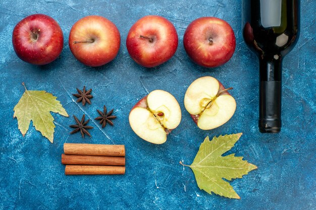 파란색 탁자에 와인 한 병이 있는 신선한 빨간 사과 잘 익은 과일 알코올 색 사진 나무