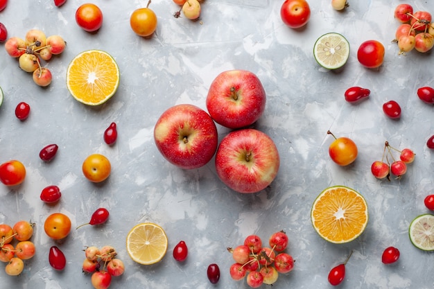 Вид сверху свежие красные яблоки с лимоном и вишней на белом столе фруктовые ягоды витамин летний сочный
