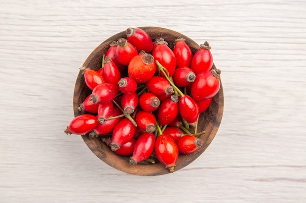 Foto gratuita vista dall'alto bacche rosse fresche all'interno di un piccolo piatto su sfondo bianco